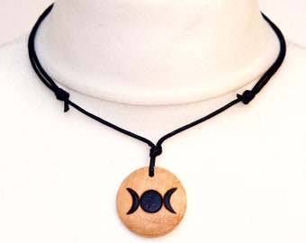 May include: A wooden pendant necklace with a black triple moon symbol on a black cord.
