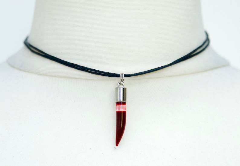 Glass chilli pepper shape vial filled with fake blood, with a silver cap on an adjustable black cord choker.