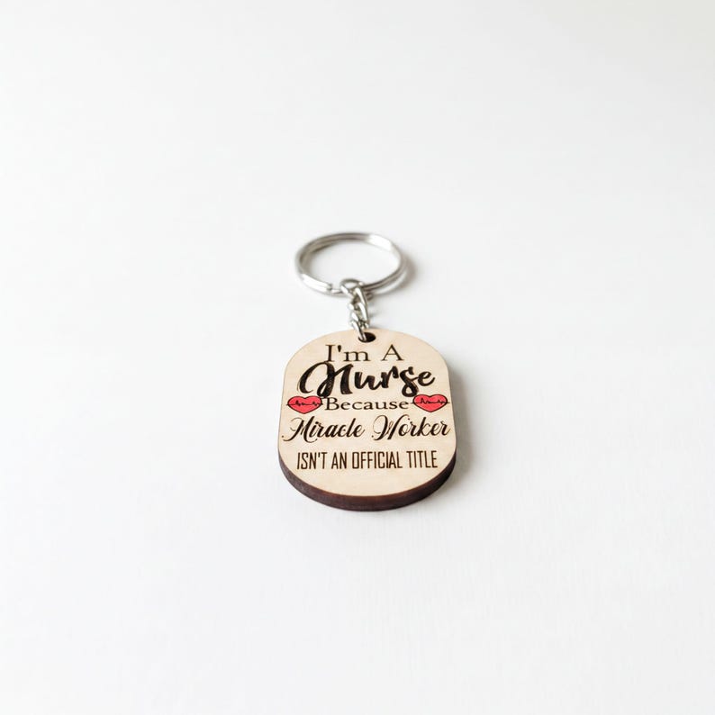 A keychain with a wooden tag that says "I'm a Nurse because Miracle Worker isn't an official title".