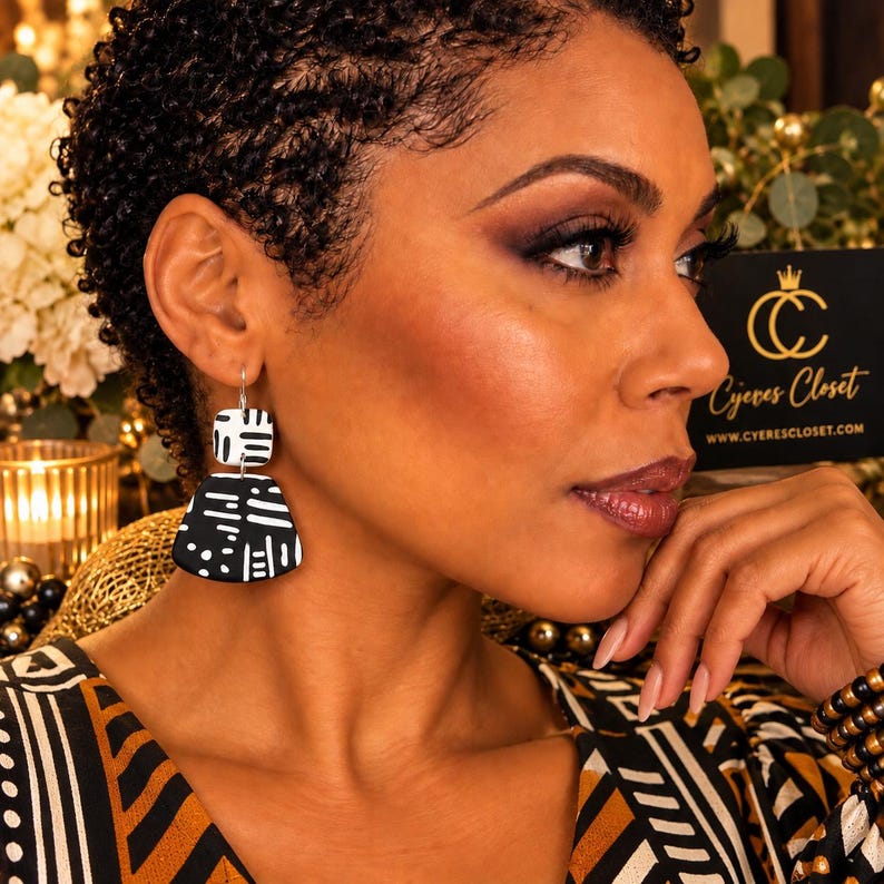 May include: Dangle earrings featuring a small white square top piece with black markings and a larger black trapezoidal bottom piece with white markings. The earrings have a silver-toned metal hook closure and a flat, matte finish design.