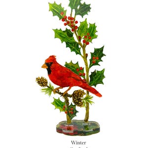 May include: A decorative acrylic standee featuring a vibrant red cardinal bird perched on a branch with green holly leaves, red berries, and brown pinecones. The base is clear with a printed design, and the text Winter Cardinal is below it.
