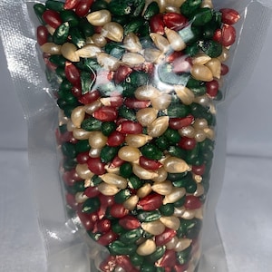 May include: A clear plastic bag filled with popcorn kernels. The kernels are a mix of red, green, and white.