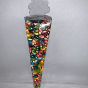 May include: A clear plastic cone filled with colorful, iridescent popcorn kernels. The cone has a decorative flower-shaped top.