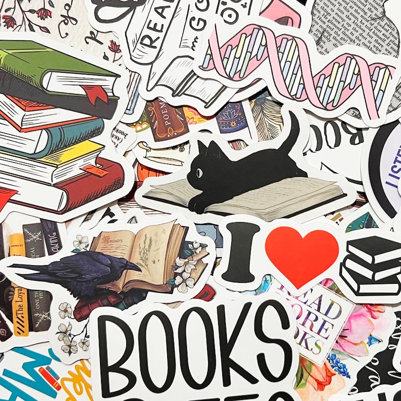Pu&ograve; includere: Una collezione di adesivi colorati a tema libri. Gli adesivi includono pile di libri, un gatto nero su un libro, un corvo su un libro e le parole "BOOKS" e "I ❤️ BOOKS".