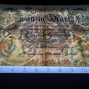 May include: An antique German Reichsbanknote, featuring ornate script and a central eagle emblem. The note displays the text "wanzig Mark" and is dated February 1914. The paper has a faded, aged appearance with red serial numbers.