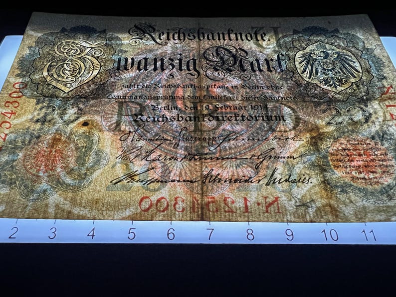 May include: An antique German Reichsbanknote, featuring ornate script and a central eagle emblem. The note displays the text "wanzig Mark" and is dated February 1914. The paper has a faded, aged appearance with red serial numbers.