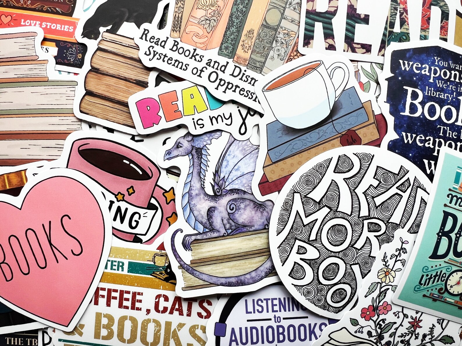 A collage of book-themed stickers such as a purple dragon on books, a cat on books, a mug with something bookish written on it, and a variety of other designs and sayings.