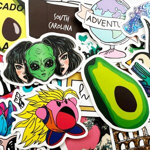 May include: A collection of colorful stickers featuring various designs, including an avocado, a globe with the word "Adventure", a cartoon character with spiky yellow hair, and a black and white bird with floral details.