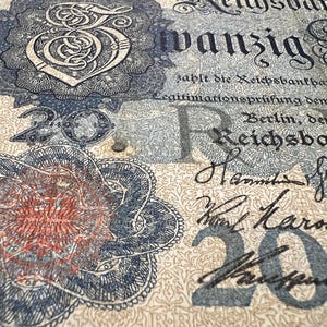 May include: Close-up of a vintage German 20 Reichsbanknote. The banknote features ornate floral designs, intricate patterns, and the number "20" in multiple locations. Text includes "Reichsbank" and handwritten signatures.