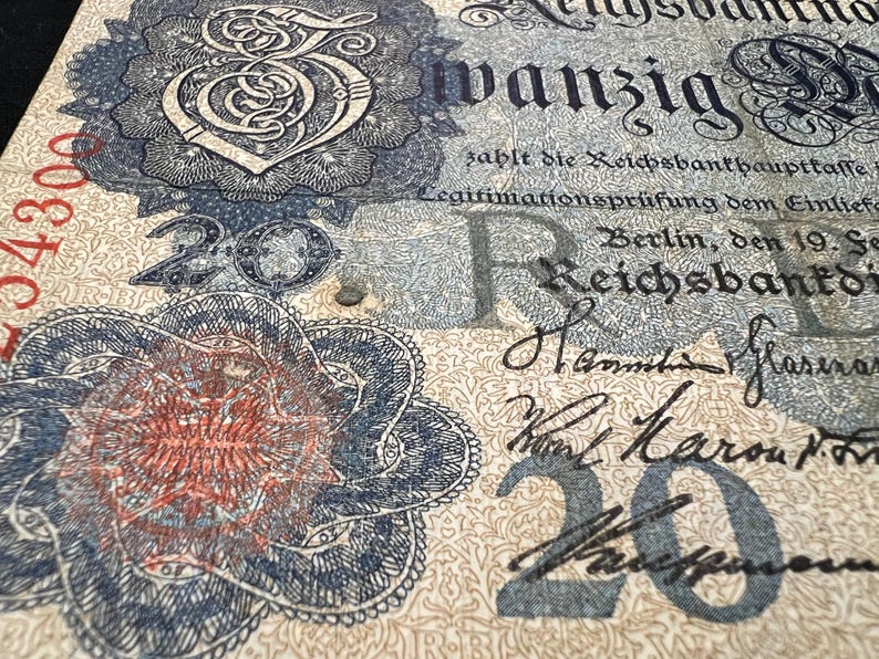 May include: Close-up of a vintage German 20 Reichsbanknote. The banknote features ornate floral designs, intricate patterns, and the number "20" in multiple locations. Text includes "Reichsbank" and handwritten signatures.