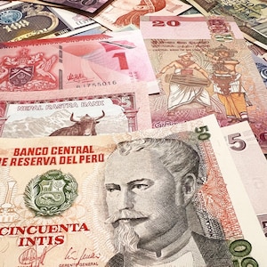 May include: A collection of international banknotes, including a red Trinidad and Tobago one-dollar bill, a Nepal Rastra Bank five-rupee note, and a Peruvian fifty-inti note. The bills display various colors and intricate designs.