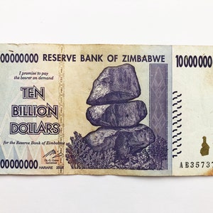 May include: A Zimbabwean ten billion dollar banknote featuring a purple image of a rock formation and the text "I promise to pay the bearer on demand TEN BILLION DOLLARS for the Reserve Bank of Zimbabwe".