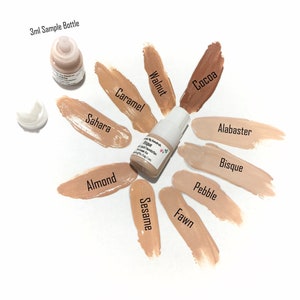 May include: A collection of liquid foundation samples in various shades, including Sahara, Almond, and Cocoa. The image features a small sample bottle and swatches of different colors, with labels like "3ml Sample Bottle".