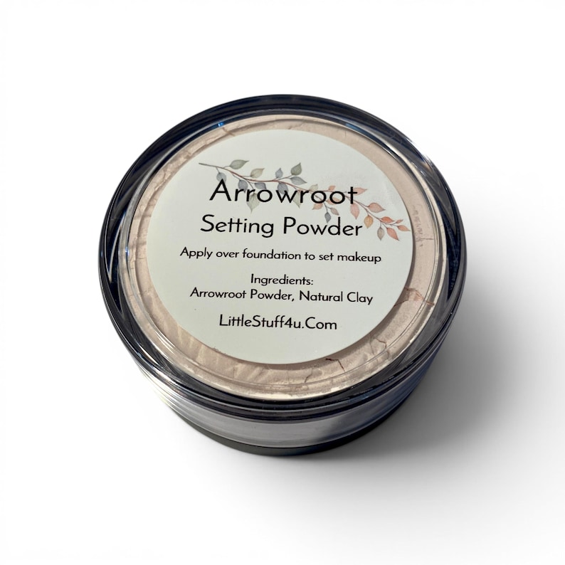 May include: A round, clear plastic container filled with beige setting powder. The label reads: Arrowroot Setting Powder, Apply over foundation to set makeup, Ingredients: Arrowroot Powder, Natural Clay, LittleStuff4u.com, with a leaf graphic.