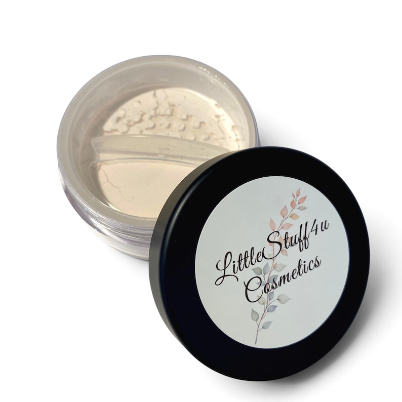 May include: A round, clear plastic cosmetic jar containing fine, off-white powder, featuring a black screw-on lid with a white circular label. The label displays the text LittleStuff 4u Cosmetics alongside a delicate, multi-coloured leaf illustration.