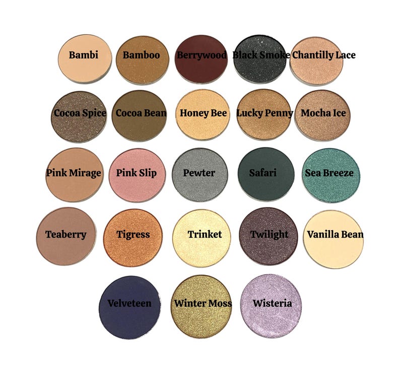 May include: A collection of twenty-two circular eyeshadow pans arranged in a grid. Each pan features a unique color including shades of brown, pink, green, gold, silver, purple, and black. The names Bambi, Bamboo, Berrywood, Black Smoke, Chantilly Lace, Cocoa Spice, Cocoa Bean, Honey Bee, Lucky Penny, Mocha Ice, Pink Mirage, Pink Slip, Pewter, Safari, Sea Breeze, Teaberry, Tigress, Trinket, Twilight, Vanilla Bean, Velveteen, Winter Moss, and Wisteria are printed on each pan.