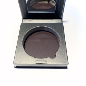 May include: A black makeup palette with a round, empty space for a pressed powder product. The palette has a mirror on the inside of the lid.