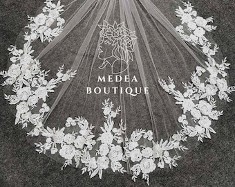 May include: White bridal veil with delicate floral lace trim. The veil is made of soft tulle and features a delicate floral pattern. The veil is perfect for a wedding or special occasion.