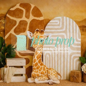 May include: A photo prop backdrop featuring a giraffe, wooden crates, and decorative elements. The backdrop includes a giraffe print and a neutral color palette. The scene is designed for photography, with the text "Photo prop" visible.