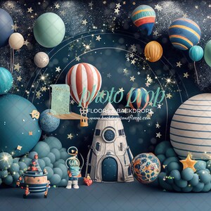 May include: A blue and white striped rocket ship with a blue door and a star on the side. The rocket ship is surrounded by blue, green, and yellow balloons, and a hot air balloon with red and white stripes. The background is a dark blue with stars and glitter.