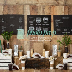 May include: A staged coffee shop scene with a wooden backdrop. The scene includes black menu boards, coffee cups, paper bags, and decorative plants. The boards display coffee and tea options. The words "photo prop" and "Floors & Backdrops" are visible.
