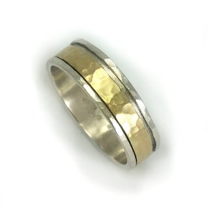 May include: A silver band with a hammered gold inlay. The band is a simple design with a subtle texture.