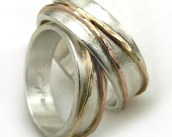 May include: A silver ring with two bands of gold and copper wire wrapped around it. The ring is textured and has a hammered finish.