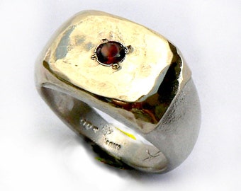 May include: A silver signet ring with a square face set with a red gemstone. The ring has a textured finish.