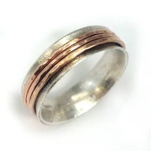 May include: A silver and copper spinning ring with a hammered texture. The ring has three bands of copper.