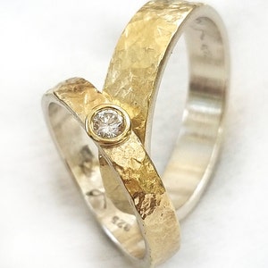 May include: Two gold wedding bands with a hammered texture. One band has a single round diamond set in the center.