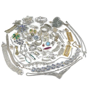 May include: A large collection of assorted vintage costume jewellery including rhinestone necklaces, bracelets, brooches, and earrings. The pieces feature clear, blue, green, and red crystals set in silver and gold-tone metal settings.