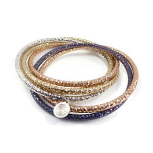 May include: Set of four metallic bangles in silver, gold, and rose gold tones. The bangles are stacked and feature a textured, sparkly finish. A small silver charm with a rose design hangs from the bottom of the stack.