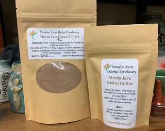 May include: Two brown paper bags with labels for Mocha Java Herbal Coffee. The bags contain a brown powder. The labels include the brand name Paradise Farm Herbal Apothecary, the product name Mocha Java Herbal Coffee, the size of the bag, and a list of organic ingredients. The labels also state that the product is caffeine free.