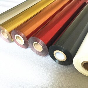 May include: Rolls of metallic foil in various colors, including gold, silver, red, and black. The foil is used for hot stamping or foil printing.