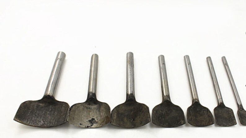 May include: Set of eight metal leather hole punches with different sizes. The punches have a silver finish and are arranged in a row from largest to smallest.