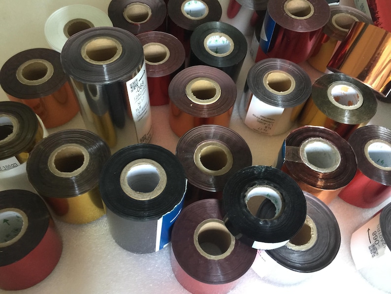 May include: Assortment of colorful foil ribbon rolls for a hot stamping machine. The rolls are various colors, including gold, silver, red, and black.