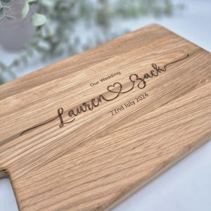 May include: A handmade wooden sign with the text "Welcome to our home" in a handwritten style. The sign is painted white with a dark stained frame. A small green plant is placed on the sign.