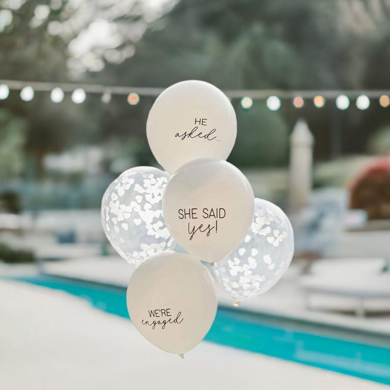 Peut inclure: Ballons blancs avec du texte noir qui dit "Il a demand&eacute;...", "Elle a dit oui !" et "Nous sommes fianc&eacute;s".