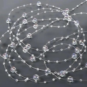 Pode incluir: Uma fita de contas transparentes iridescentes enfiadas em um fio fino. As contas são de vários tamanhos e criam um efeito brilhante.