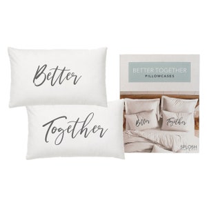 May include: Two white pillowcases with the words "Better" and "Together" in black script. The pillowcases are displayed on a bed with a white duvet cover and a light brown throw blanket. The image also includes a packaging label with the text "Better Together Pillowcases" and the brand name "SPLOSH Home & Gift".