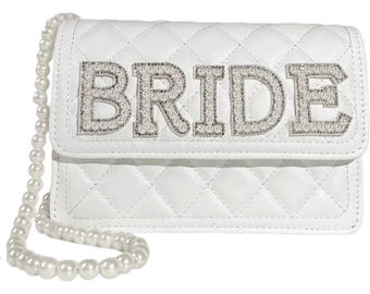 May include: White quilted handbag with a pearl chain strap. The front flap has the word "BRIDE" spelled out in large letters with pearl embellishments.