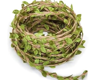 Puede incluir: Un rollo de cuerda con hojas de tela verde tejidas en la cuerda. La cuerda es marrón y las hojas son de color verde claro.