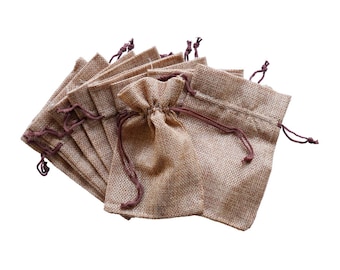 Könnte beinhalten: Ein Stapel kleiner brauner Jutesäcke mit braunen Kordeln. Die Säcke sind aus einem natürlichen, gewebten Stoff gefertigt und eignen sich perfekt zum Verpacken von kleinen Geschenken oder Gastgeschenken.