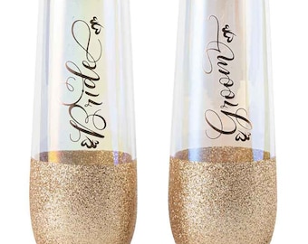 May include: Two champagne flutes with gold glitter bottoms. One flute says "Mr. Groom" and the other says "Mrs. Bride".
