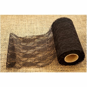 Peut inclure: Un rouleau de ruban en dentelle noire avec un motif floral délicat. Le ruban est enroulé sur un tube en carton et repose sur une surface en toile de jute.