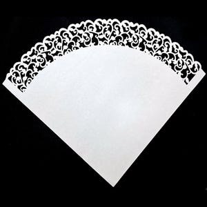 Könnte beinhalten: Weißer Papierkegel mit einem dekorativen Spitzenrand. Der Kegel besteht aus dünnem Papier und hat einen gewellten Rand.