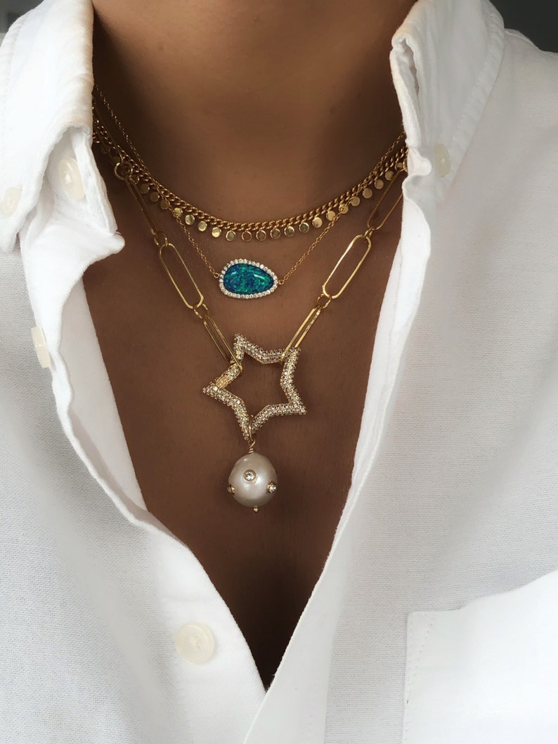 May include: Layered gold necklaces with a blue opal pendant, a star-shaped pendant with clear stones, and a pearl pendant.