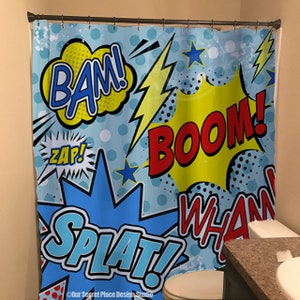 May include: A blue shower curtain with a comic book theme. The shower curtain features yellow, red, and blue speech bubbles with the words "BAM!", "ZAP!", "BOOM!", "WHAM!" and "SPLAT!" printed on them.