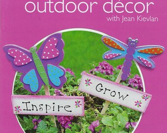 Könnte beinhalten: Broschüre für Außendekoration mit Gartensteckern in Form von Schmetterlingen und Libellen. Die Stecker tragen die Wörter "Inspire" und "Grow". Die Broschüre trägt den Titel "outdoor décor" und enthält den Text "dekorationsideen für Wohnräume im Freien".