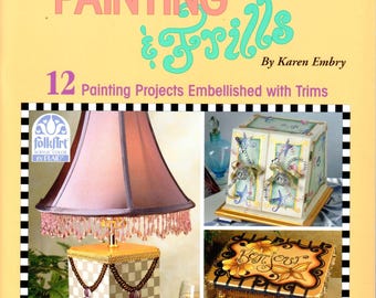 May include: A book cover for "Painting & Frills" by Karen Embry, showcasing decorative painting projects. The cover displays a lamp, a box, a table, and a decorative piece, all embellished with trims. The book contains 12 painting projects.
